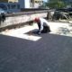 roofer cutting protection board for drain installation.