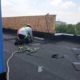 experienced Roofer wearing a harness cutting flashing for balconies.